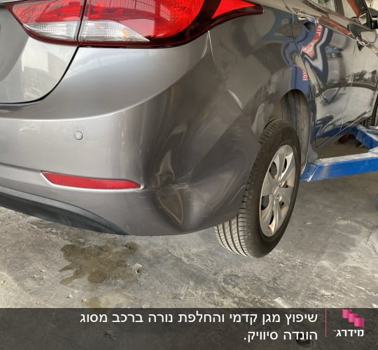 רכב אפור עם פגוש אחורי פגום במוסך